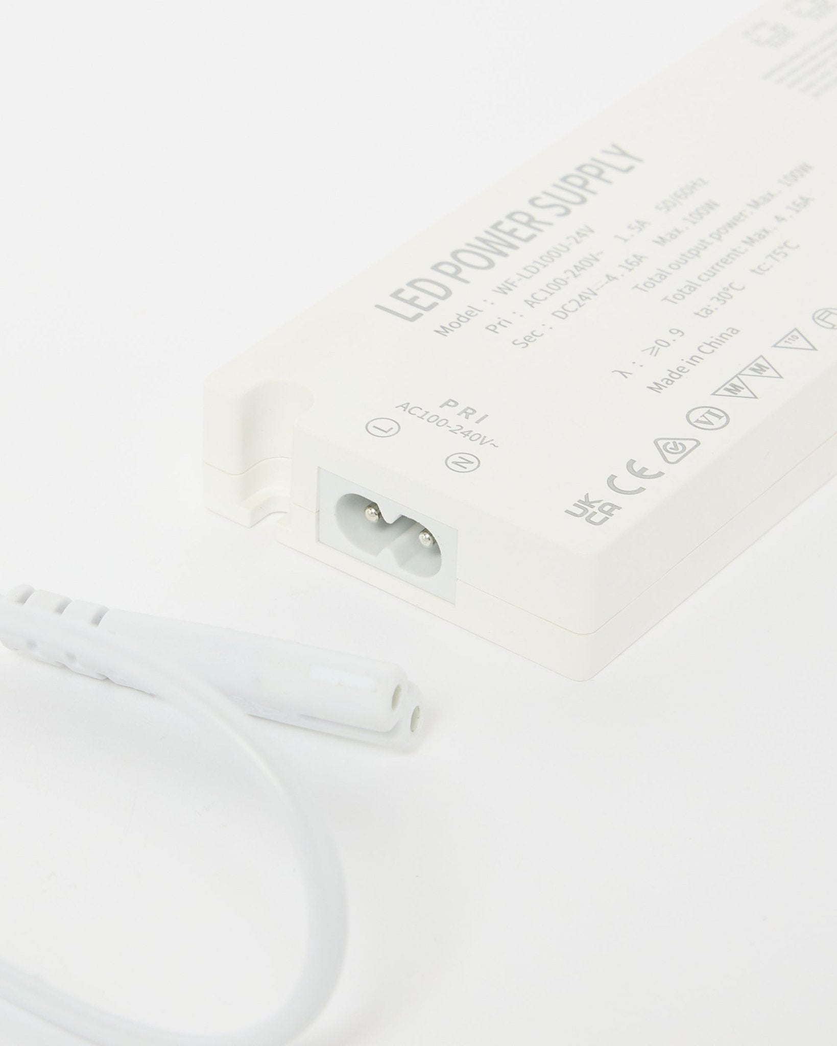 Close-up of a beige WoodUpp Lumi LED striplights power supply (240 cm) showing technical details, with an adjacent cable, designed for Nordic acoustic panel installations.