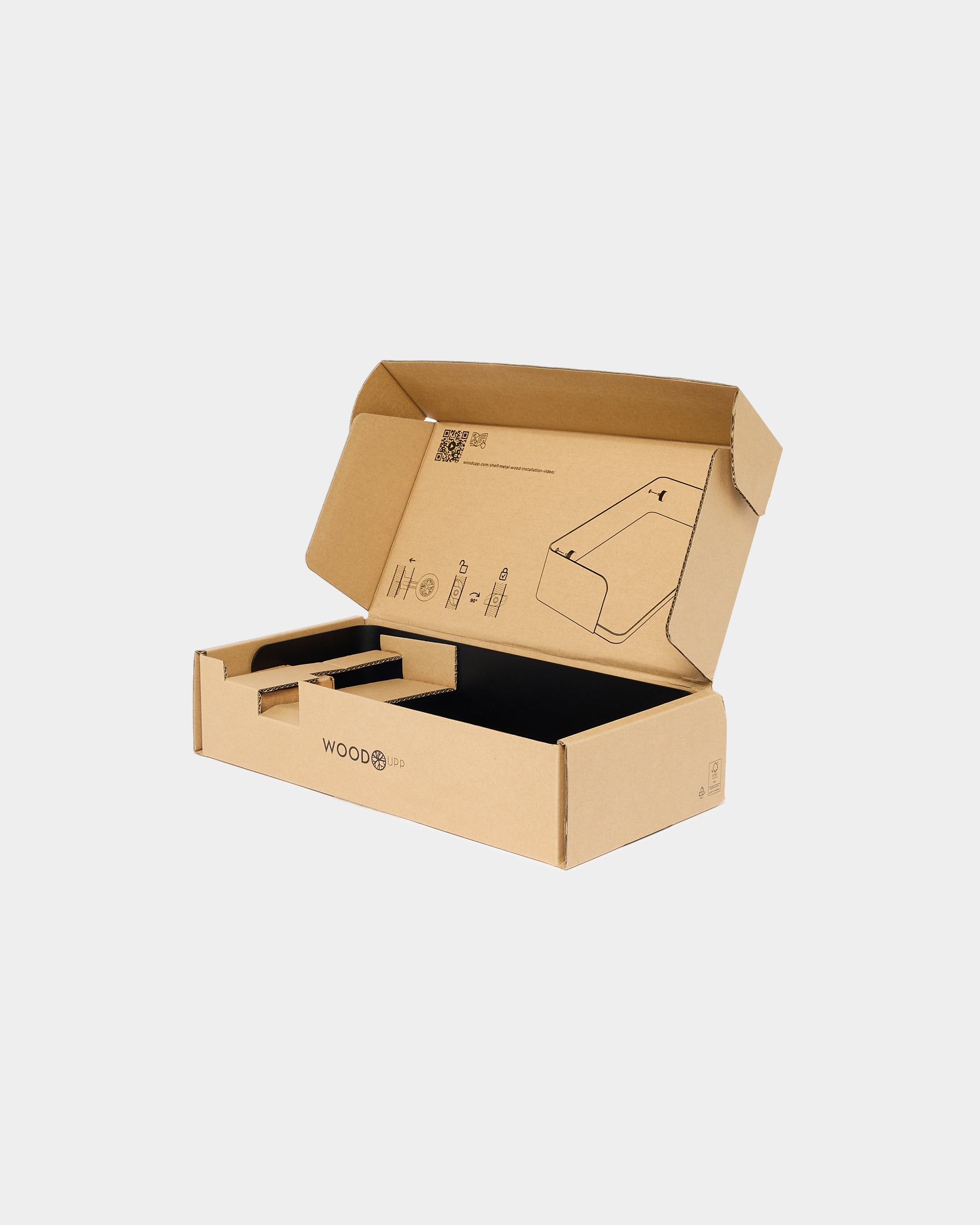 Open cardboard box containing assembly instructions, organized compartments, and WOOD label on the side, showing packaging for Akupanel acoustic wood panels.