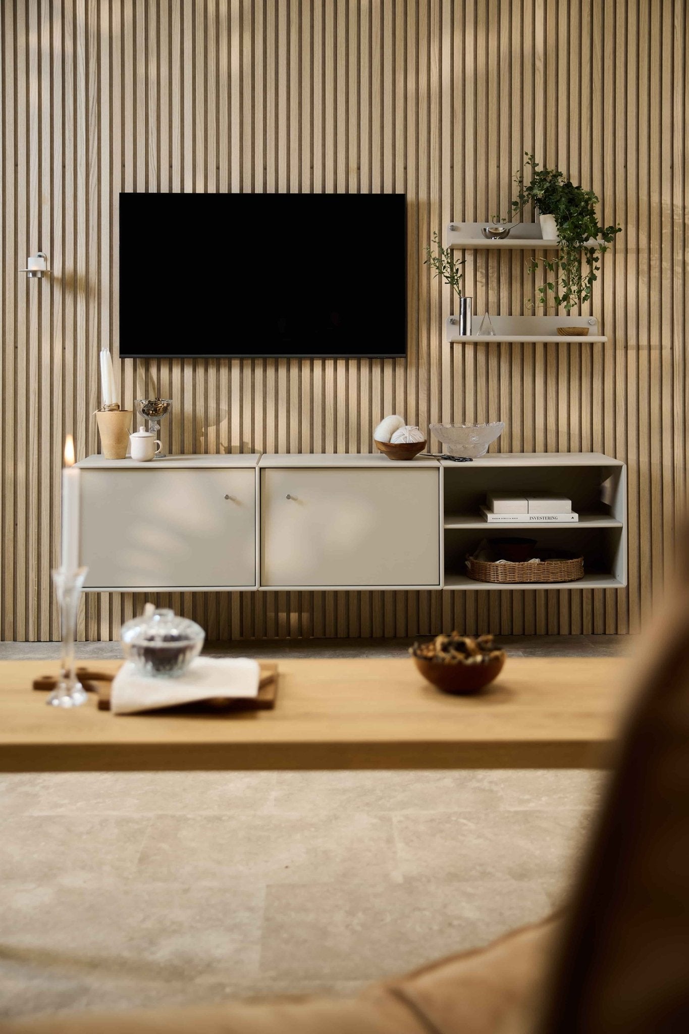 Modern living room with Arka TV Console by WoodUpp, modular seating, Nordic shelves with plants and decor, and a candle on the coffee table.