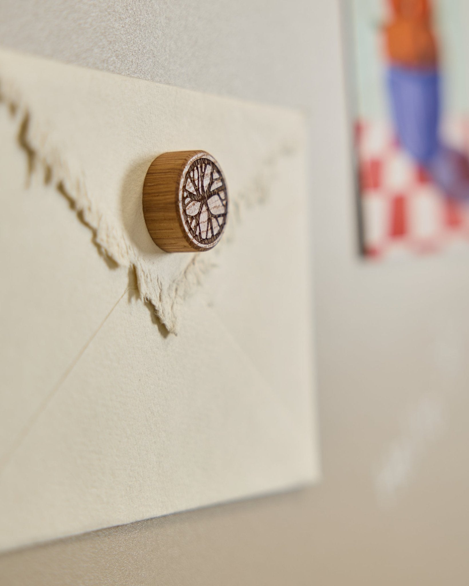 A cream envelope is pinned to an acoustic panel with a Norr Natural Oak magnet by WoodUpp, featuring a minimalist tree design.