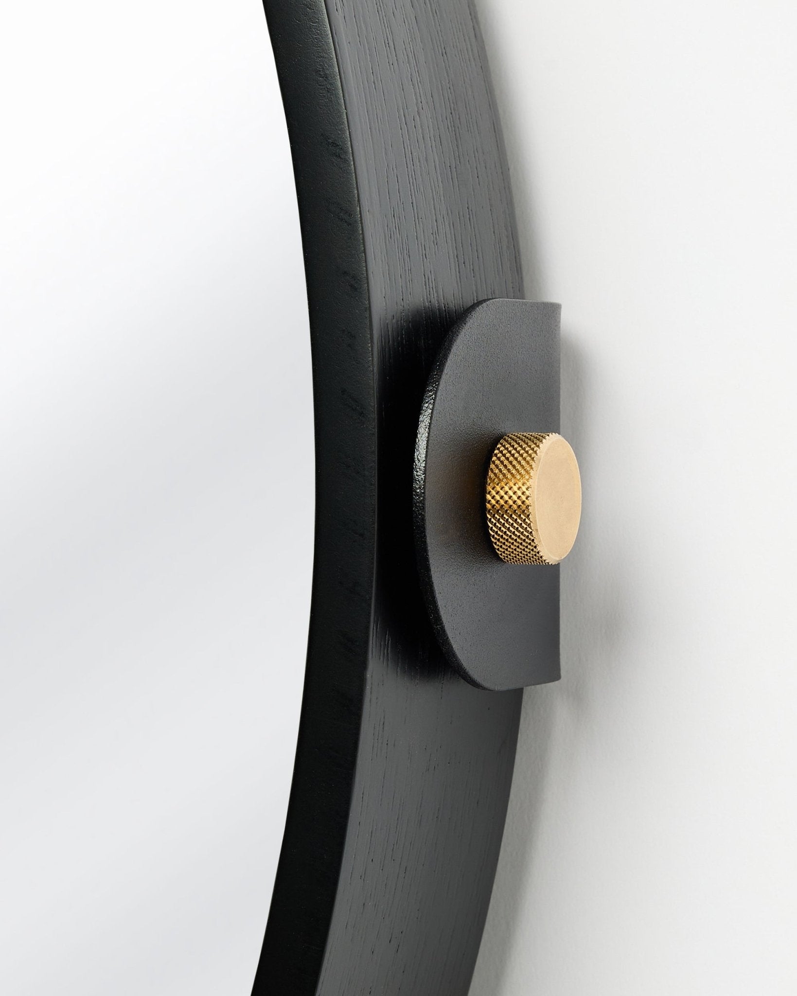 Detail of the Linn | Mirror / Black Oak acoustic panel by WoodUpp, mounted on the wall with a gold knob and adjustable tilt.