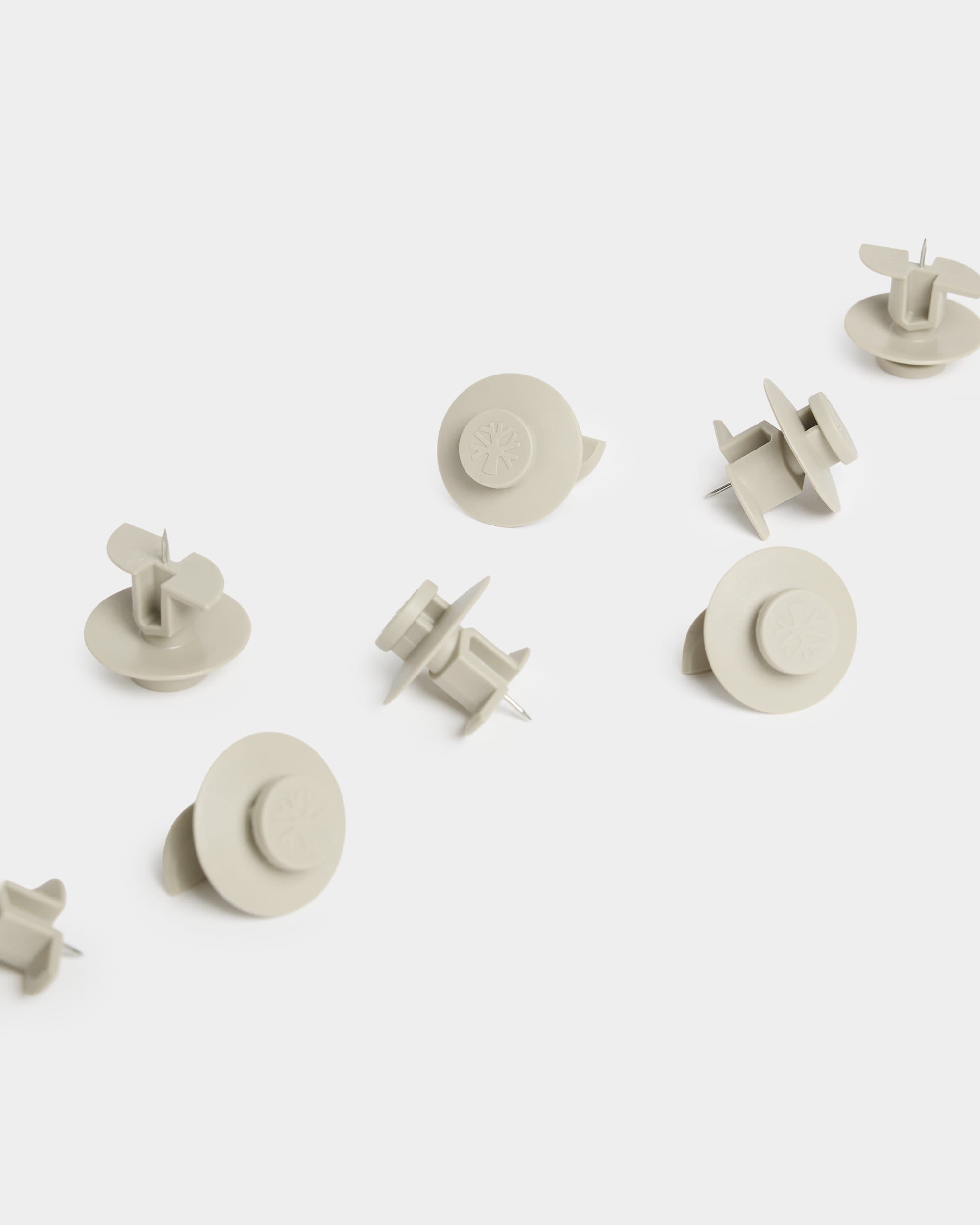 Ten beige WoodUpp Dupps push pins (Light) with circular heads are arranged on a white surface, designed for use with acoustic panel accessories.