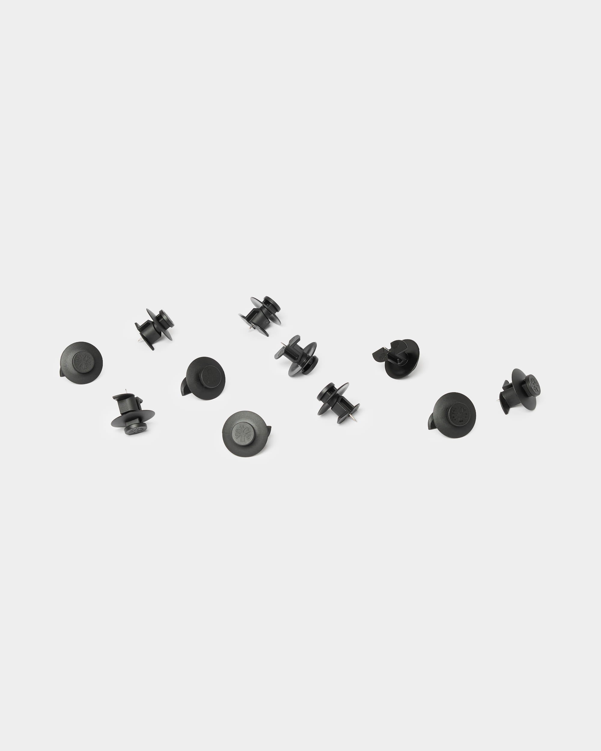 Ten WoodUpp Dupps light black accessories are scattered on a plain white background, designed for use with Akupanel acoustic wood panels.