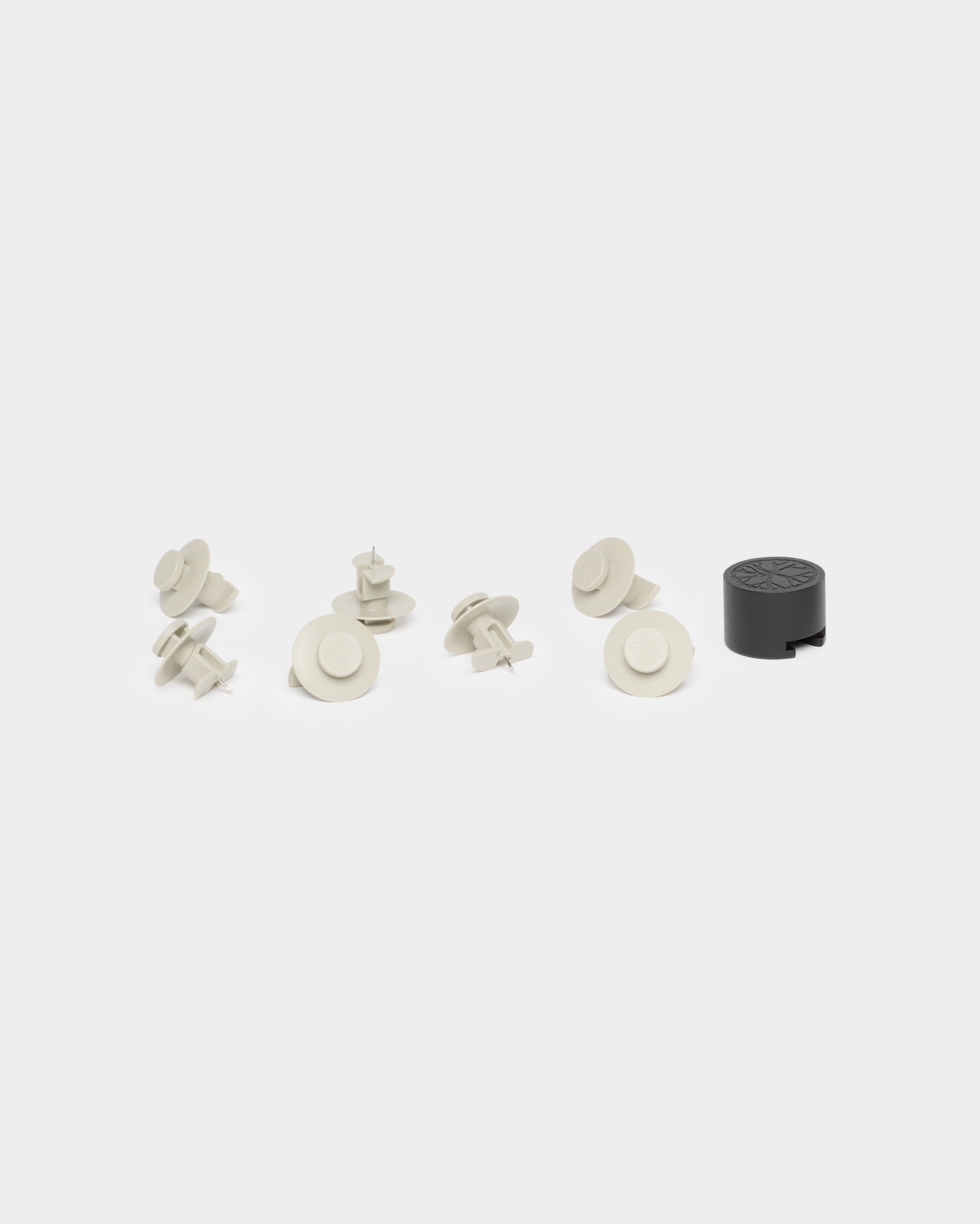 Seven beige fasteners and one black installation tool for WoodUpp Akupanel, displayed on a white background.
