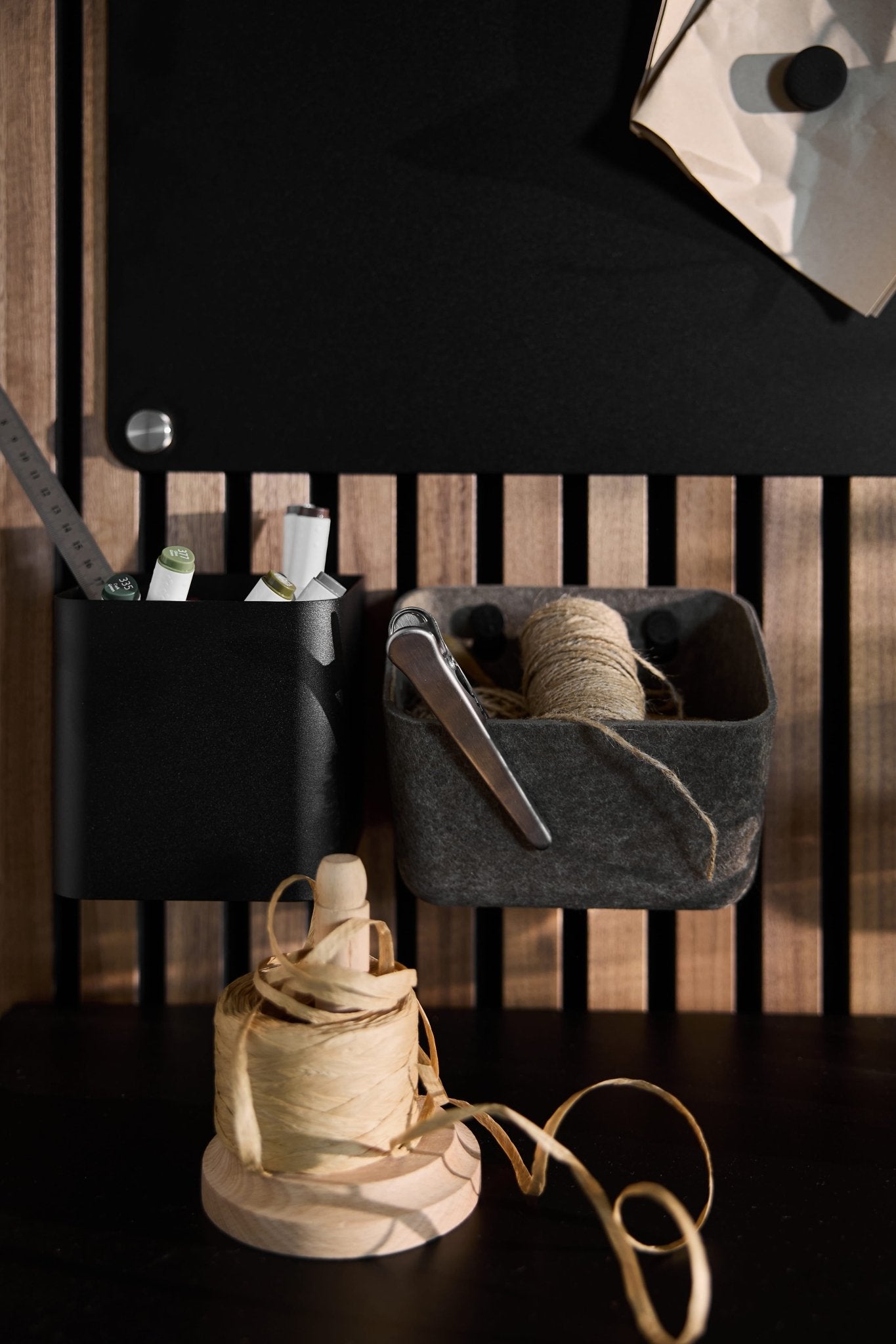 Luva dark warm grey felt containers by WoodUpp hold pens, scissors, and twine on a wood Akupanel; extra twine rests below.