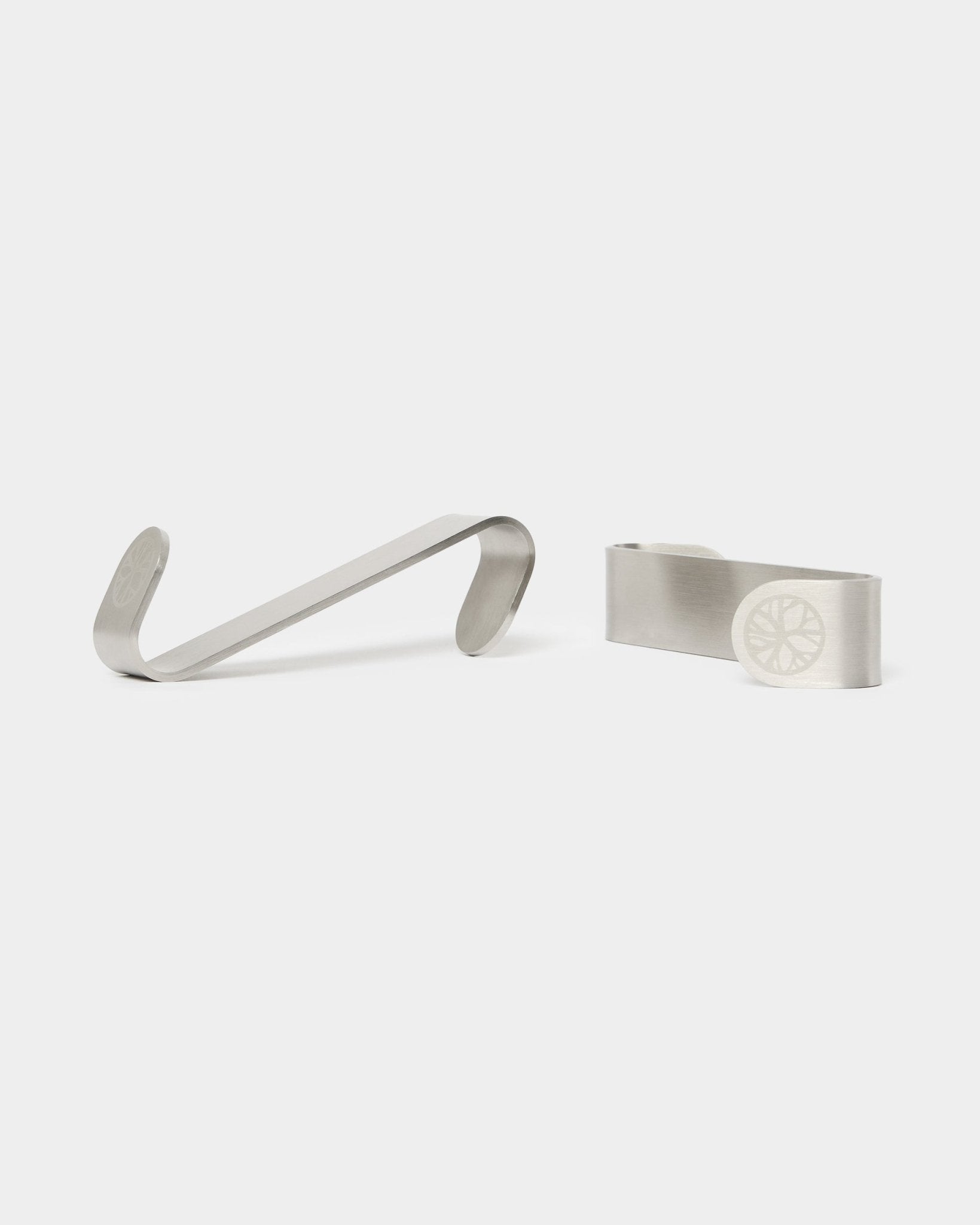 WoodUpp Alva S-Hook BM1 and BM2 money clips, two stainless steel accessories featuring engraved wheel designs, designed for Nordic acoustic wood panels.