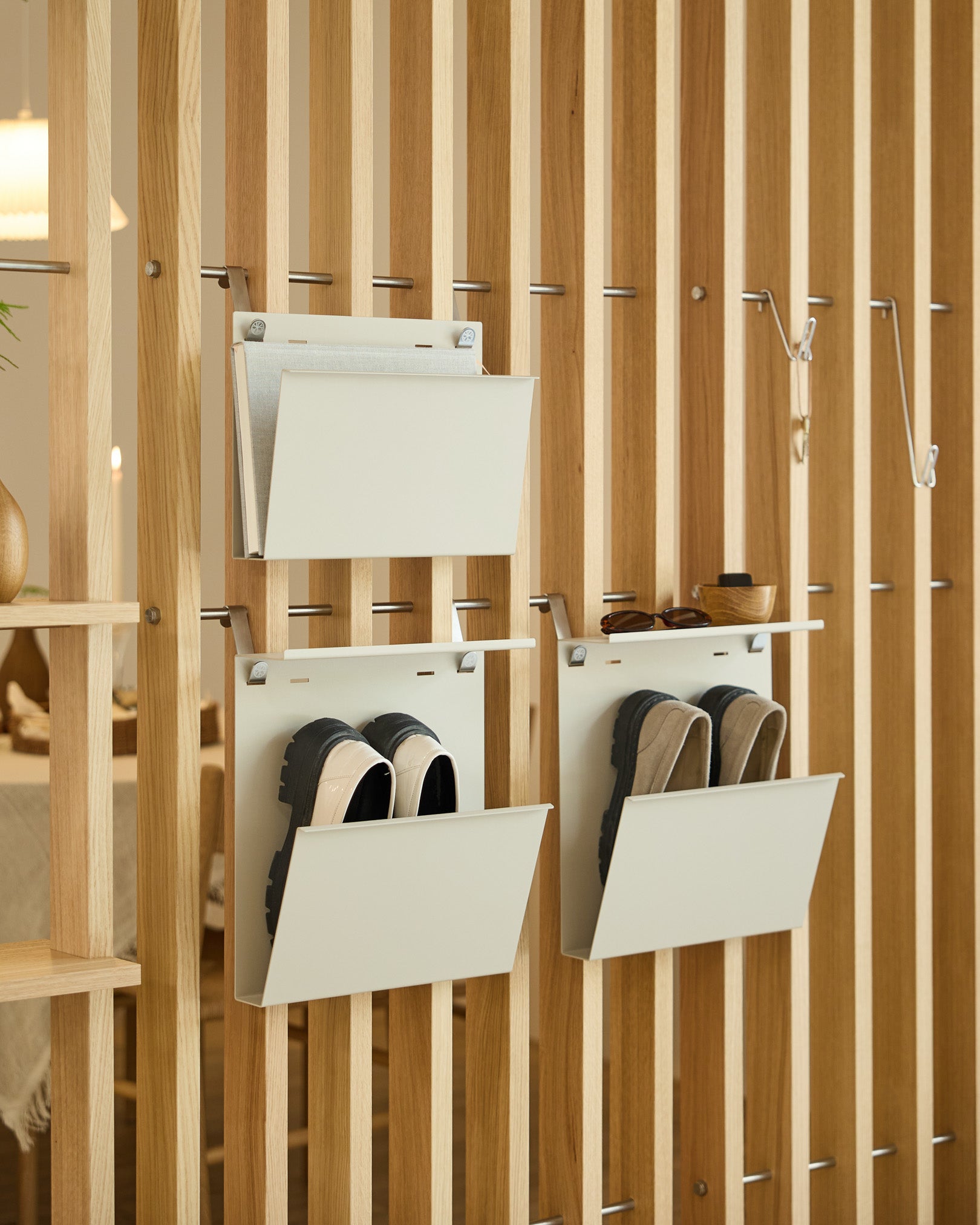 The Nell Magazine Storage by WoodUpp in beige is attached to a vertical room divider, providing organized storage for magazines and small items.