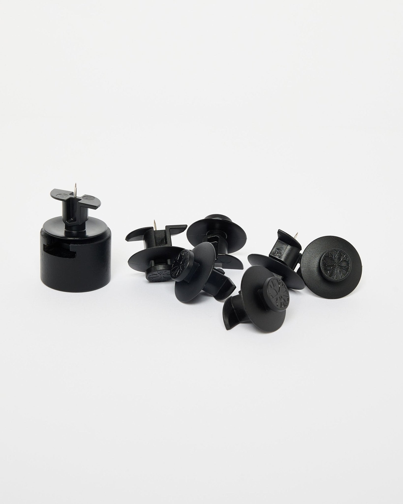 Dupps by WoodUpp: seven black plastic security tags, one installation tool, and nylon brackets arranged on a plain white background.