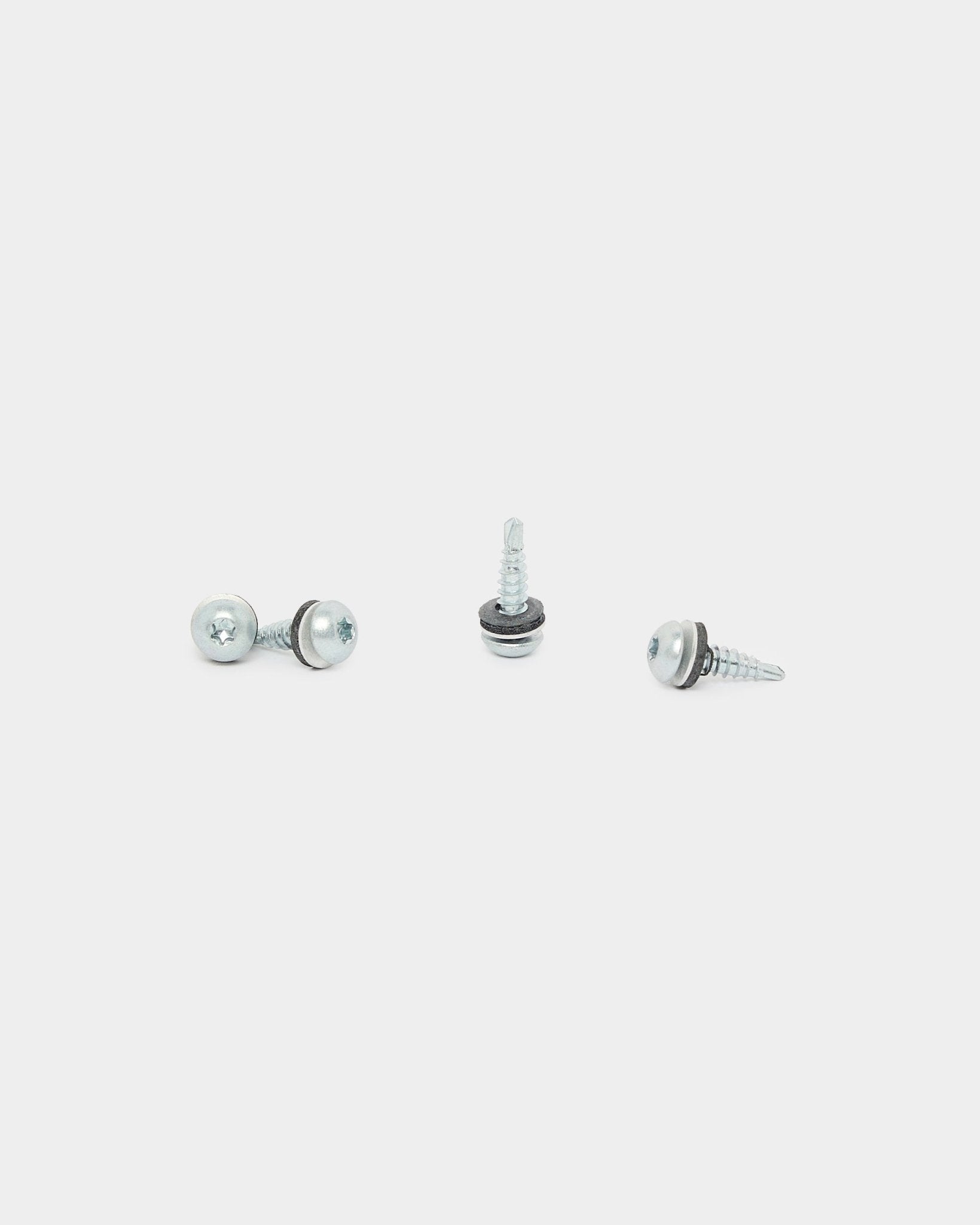Three black WoodUpp Backside Screws (4.8x19, Ø10 washer, TX20), used for acoustic panel installation, are arranged in different directions on a white background.