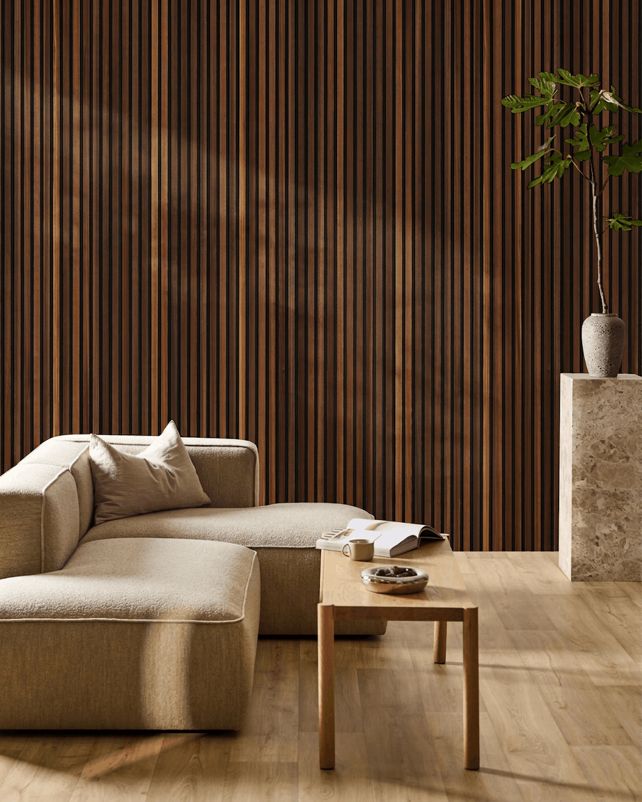 Minimalist living room featuring a beige sofa, coffee table with open book, tall plant, and WoodUpp Akupanel acoustic wood panel in smoked larch on the wall.